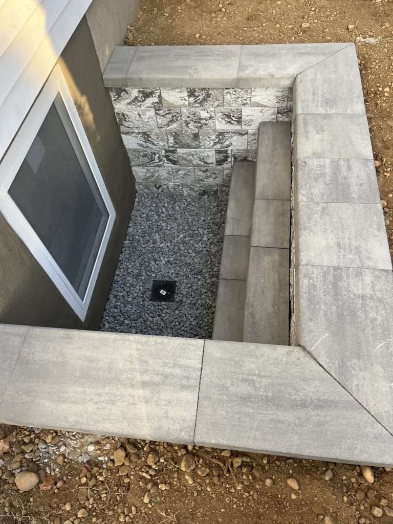 Cambridge ArmorTec block egress window well with built-in steps, drainage stone, floor drain and a new egress window on Long Island, NY
