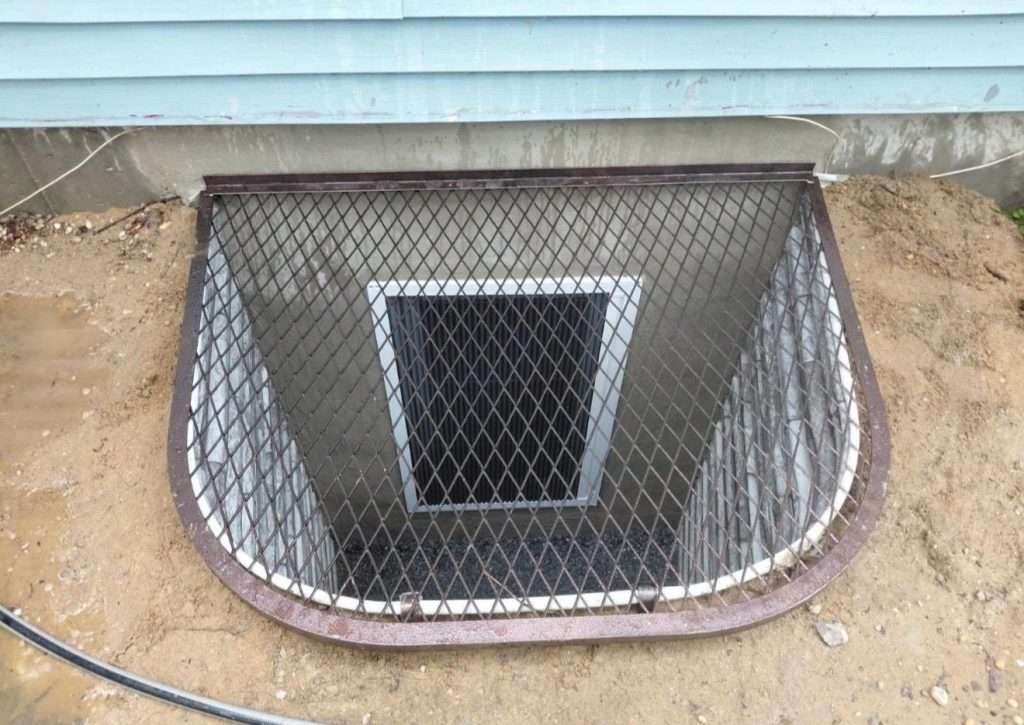 Egress window well protected by a metal frame and mesh grate cover on Long Island, NY